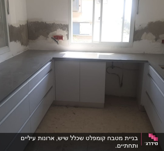 מטבח עם ארונות לבנים ומשטח עבודה אפור